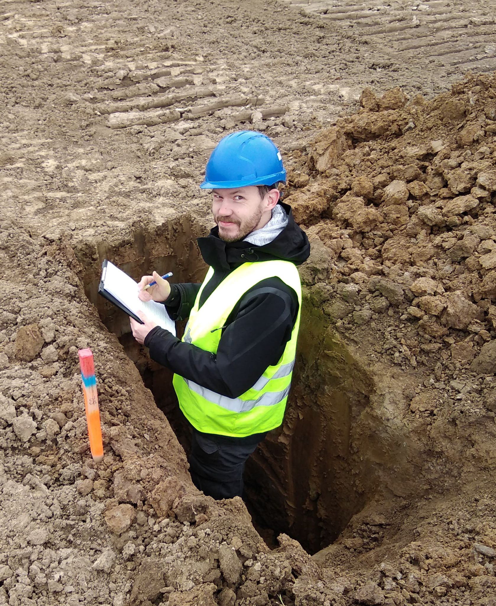 Geolog zapisuje výsledky průzkumu ve vykopané sondě